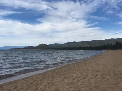 a beach with a body of water and mountains at Lake Village Resort 3 bedroom condo in Zephyr Cove