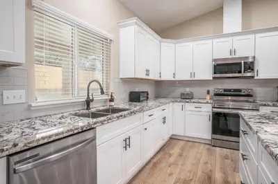 a kitchen with white cabinets and marble counter tops at The Oakhurst Oasis - Family & Fun Edition in Oakhurst