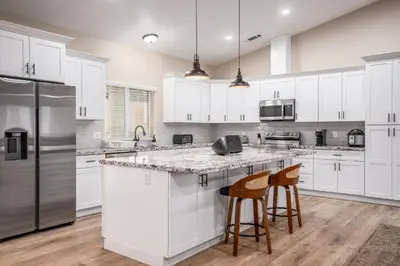 a kitchen with white cabinets and a island with bar stools at The Oakhurst Oasis - Family & Fun Edition in Oakhurst