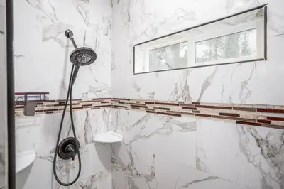 a shower in a bathroom with marble walls and a window at The Oakhurst Oasis - Family & Fun Edition in Oakhurst