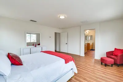 a bedroom with a white bed and a red chair at 7 Mi to Lake Yosemite Family Home with Fenced Yard in Merced
