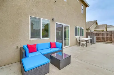 a blue couch with red pillows on a patio at 7 Mi to Lake Yosemite Family Home with Fenced Yard in Merced