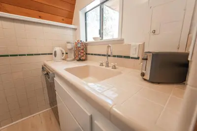 a white bathroom with a sink and a window at Sequoia Vintage A-frame River Retreat in Three Rivers