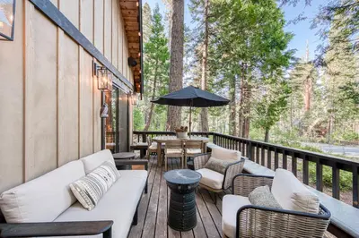 a deck with couches and tables and an umbrella at Songbird Cabin at Chambers by Tahoe Getaways - Pet-Friendly 2 BR with HOA Access in Homewood