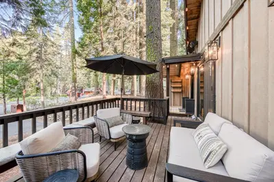 a deck with couches and chairs and an umbrella at Songbird Cabin at Chambers by Tahoe Getaways - Pet-Friendly 2 BR with HOA Access in Homewood