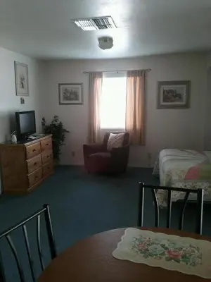 a bedroom with a bed and a chair and a table at Bishop Village Motel in Bishop