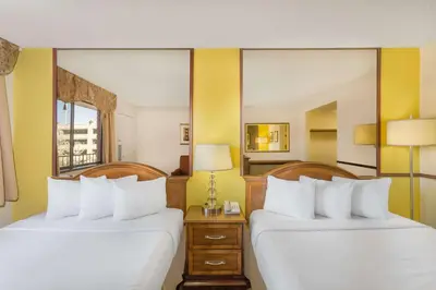 a hotel room with two beds and a mirror at Travelodge by Wyndham Reno in Reno