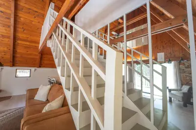 a white staircase in a house with wooden ceilings at Sequoia Vintage A-frame River Retreat in Three Rivers