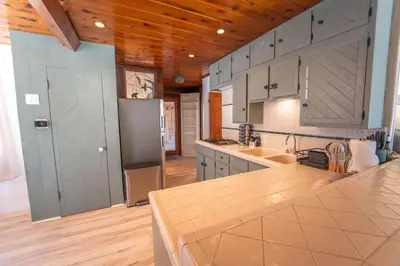 a kitchen with white cabinets and a wooden ceiling at Sequoia Vintage A-frame River Retreat in Three Rivers