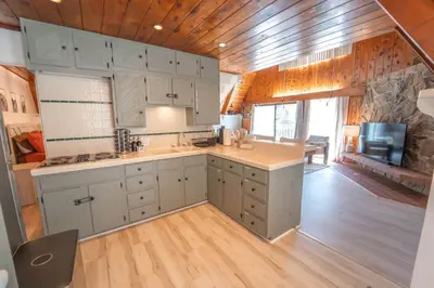a kitchen with white cabinets and a stone wall at Sequoia Vintage A-frame River Retreat in Three Rivers