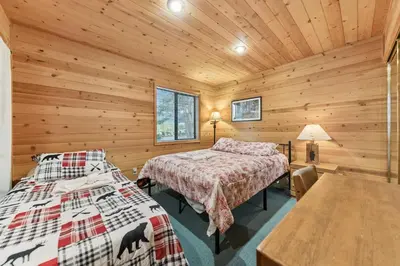 two beds in a log cabin bedroom with wooden walls at 589 Danube Drive condo in South Lake Tahoe