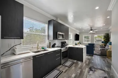 a kitchen with black cabinets and a living room at Walk to UC Davis Medical Center! Duplex with Patio in Sacramento