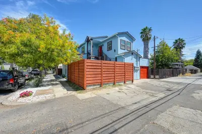a house on the side of a street with a fence at Walk to UC Davis Medical Center! Duplex with Patio in Sacramento