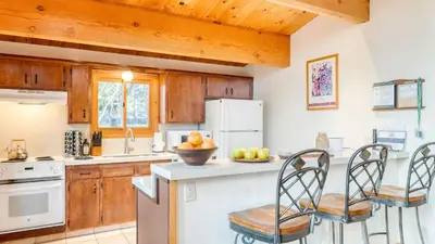 a kitchen with wooden cabinets and a counter with chairs at Sleeps 20 2 Homes Near Ski Resort Beach Lake Access Pool Homewood in Tahoma