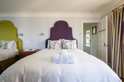a bedroom with a large white bed with a blue headboard at Grand Wine Country 6BR Retreat Hot Tub & Views in San Martin