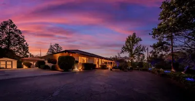 a house with a sunset in the sky at Sierra View Retreat with Newly Installed Hot tub! in Oakhurst