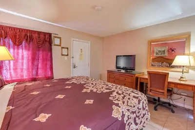 a bedroom with a bed and a desk with a computer at Los Banos Motel in Los Banos