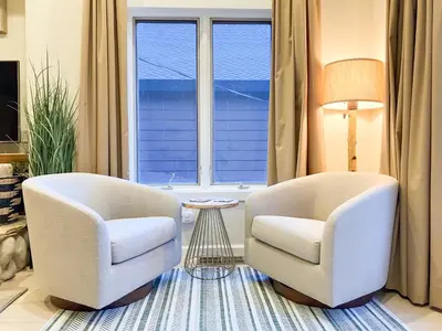 two white chairs in a living room with a window at Boom Chalet Yosemite in Oakhurst