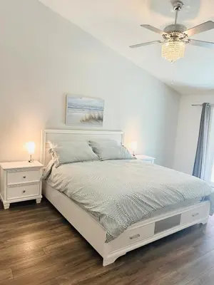 a bedroom with a white bed and a ceiling fan at Contemporary, newly renovated and great location in Fresno