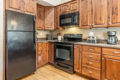 a kitchen with wooden cabinets and a stainless steel refrigerator at Updated1849 Townhome #611, Steps to Canyon Lodge 4 Bed/3BA, hot tubs, game rm, sauna! in Mammoth Lakes