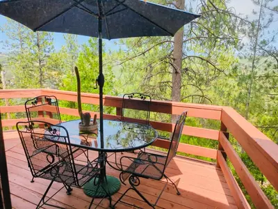 a table and chairs on a deck with an umbrella at Lakeview Yosemite 3B2b Private House - Panoramic Sauna - Seasonal Hot Tub Jacuzzi in Groveland