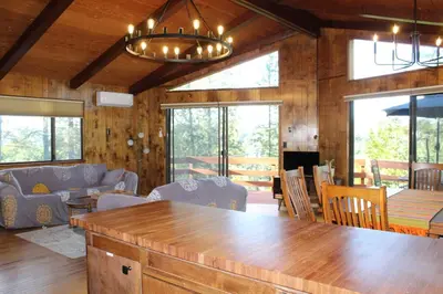 a living room with wooden walls and a large wooden table at Lakeview Yosemite 3B2b Private House - Panoramic Sauna - Seasonal Hot Tub Jacuzzi in Groveland