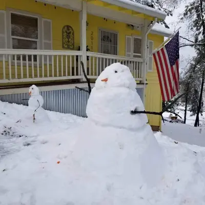 two snowmen in front of a house with an american flag at Cozy Mountain Cabin Yosemite Dodge Ridge Ski in Tuolumne