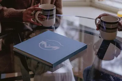 a person holding two coffee cups on a glass table at Cozy Mountain Cabin Yosemite Dodge Ridge Ski in Tuolumne