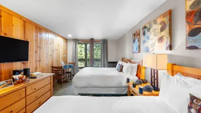 a hotel room with two beds and a flat screen tv at Cozy Northstar Village Escape w Forest Views Easy Lift Access Alpineglow Vista by AvantStay in Truckee