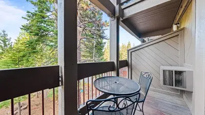 a patio with a table and chairs on a balcony at Cozy Northstar Village Escape w Forest Views Easy Lift Access Alpineglow Vista by AvantStay in Truckee
