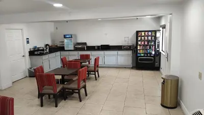 a kitchen with a table and chairs and a refrigerator at Rancho Cordova Inn in Rancho Cordova