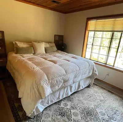 a bedroom with a large white bed with a window at Little Bear Lodge in Springville