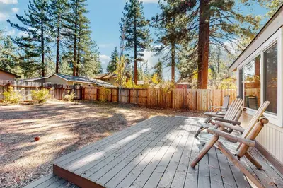 a patio with two wooden chairs and a fence at Golden Pine Lodge in South Lake Tahoe
