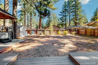 a large yard with a fence and trees at Golden Pine Lodge in South Lake Tahoe