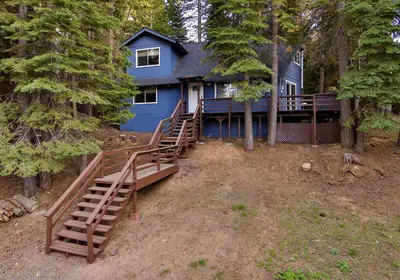 a blue house in the middle of the forest at Iroquois Ridge Hot Tub Near Lake Tahoe & Skiing in South Lake Tahoe