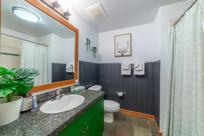 a bathroom with a sink and a toilet and a mirror at Posh Village 2/2; Ski-In/Out + Premiere Perks! in Mammoth Lakes