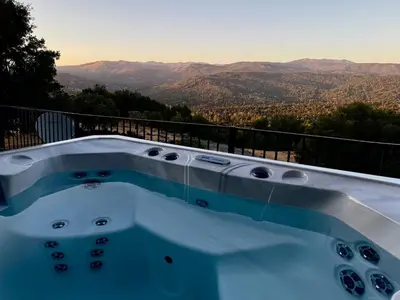 a hot tub with a view of the mountains at NEW LISTING, Near Yosemite South Gate entrance and town, King bed, Hot Tub, BBQ, Firepit & Mountain Views in Oakhurst
