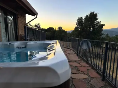 a hot tub on a balcony of a house at NEW LISTING, Near Yosemite South Gate entrance and town, King bed, Hot Tub, BBQ, Firepit & Mountain Views in Oakhurst