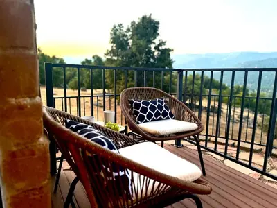 two wicker chairs and a table on a balcony at NEW LISTING, Near Yosemite South Gate entrance and town, King bed, Hot Tub, BBQ, Firepit & Mountain Views in Oakhurst