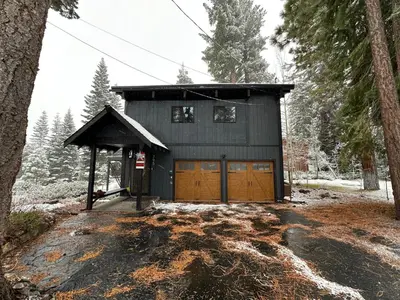 a house with two garage doors in the woods at Modern Rustic Lux Tahoe Cabin in Carnelian Bay