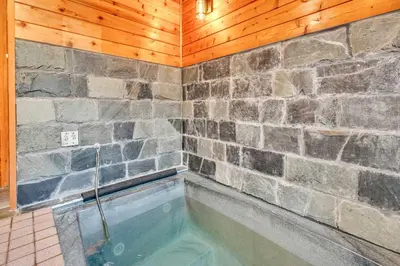 a hot tub in a room with a stone wall at Wooded Getaway Steam Shower plus Hot Tub in Tahoe City