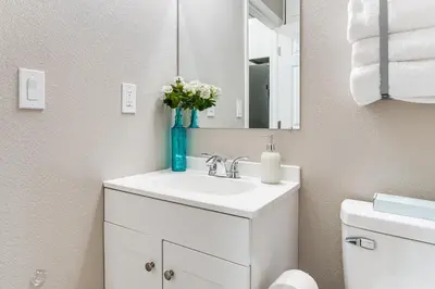 a white bathroom with a sink and a mirror at Couples Retreat! Shop, Dine, Explore Dtwn Oakdale in Oakdale