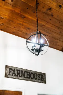 a lamp hanging from a ceiling with a farmhouse sign at OctaFarmRetreat - Gateway To Sequoia Natl Park in Visalia