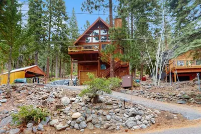 a log cabin in the woods with a pile of rocks at Dog-Friendly Retreat with Lake Views in Kings Beach in Kings Beach
