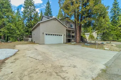 a house with a garage in front of a driveway at The Trailhead Hot Tub, Hikes & Night Skies in Shaver Lake