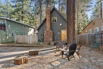 a house in the woods with a chair and trees at HCH0648 - Larchwood Lodge home in South Lake Tahoe