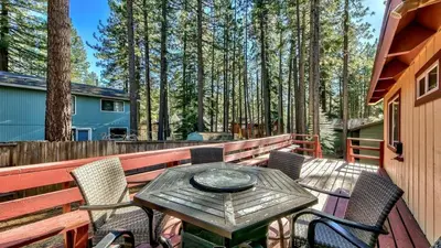 a wooden table and chairs on a deck with trees at COH0809 - Brule Haven home in South Lake Tahoe