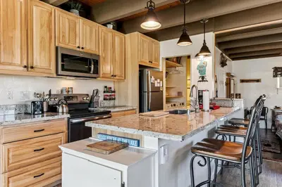 a kitchen with wooden cabinets and a island with bar stools at Tahoe Keys Studio Condo in South Lake Tahoe