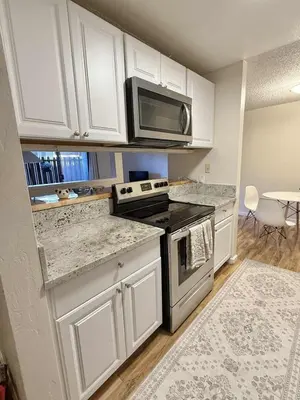 a kitchen with white cabinets and a stove and microwave at Near Lake, Golf and Tennis - Reno Condo in Reno