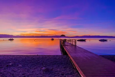 a dock on a beach with boats in the water at Lake Tahoe West Shore Lake Front 5 bedroom Cabin in Homewood